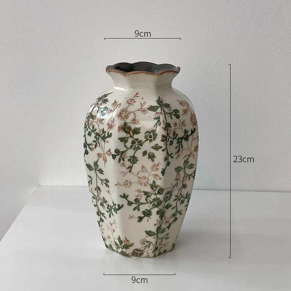 A rustic ceramic milk pitcher with a cracked glaze and pastoral design, featuring green foliage patterns.