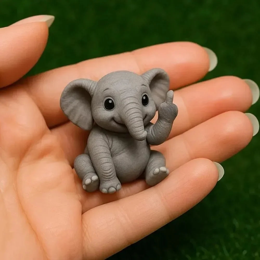 A small gray resin elephant statue is held in a person's hand against a green background.