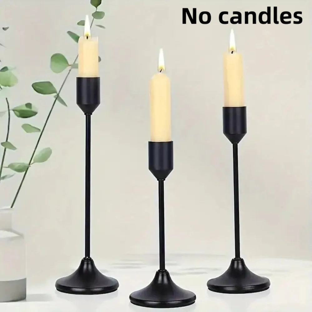 A set of three black minimalist retro tabletop candle holders with white candles on a white surface.