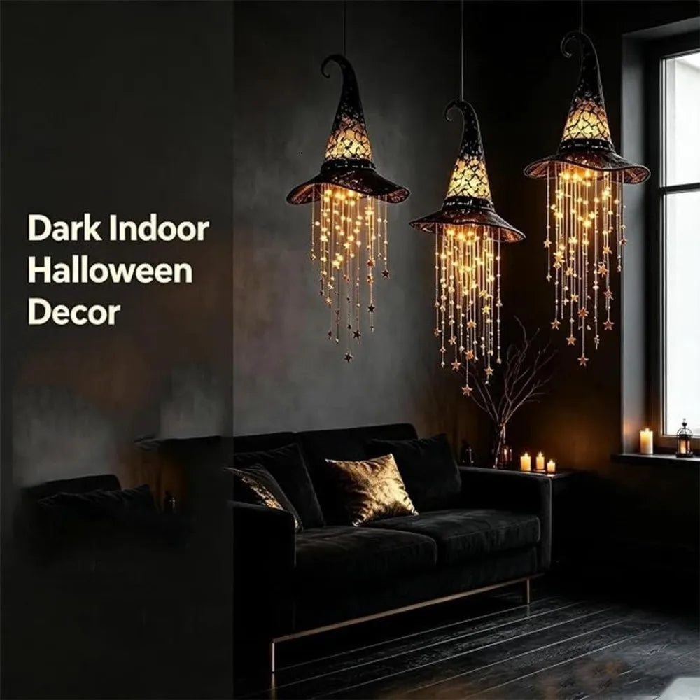 Dark indoor Halloween decor featuring three glowing witch hat chandeliers with hanging star tassels.