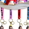 A collection of silicone Jesus keychains with colorful straps hanging from a white surface.