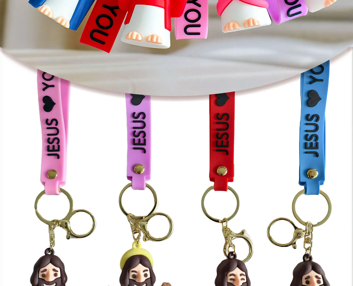 A collection of silicone Jesus keychains with colorful straps hanging from a white surface.