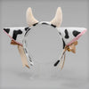 A headband featuring cow ears made of light pink and black faux fur with a ribbon bow.