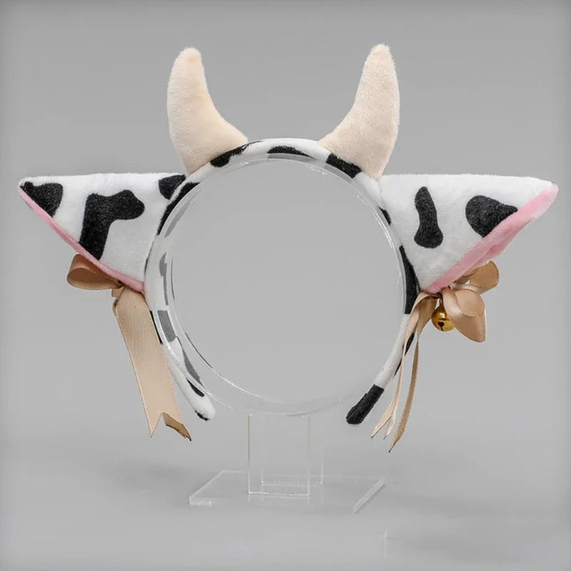 A headband featuring cow ears made of light pink and black faux fur with a ribbon bow.