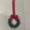 Set of four mini Christmas wreaths decorated with evergreen branches, red berries, and pink ribbon bows.