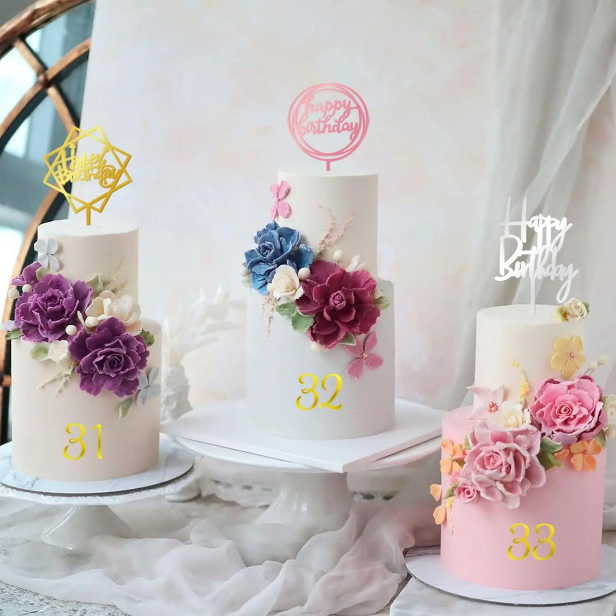 A tiered white cake decorated with purple and pink floral accents and a gold number 31, 32, and 33.
