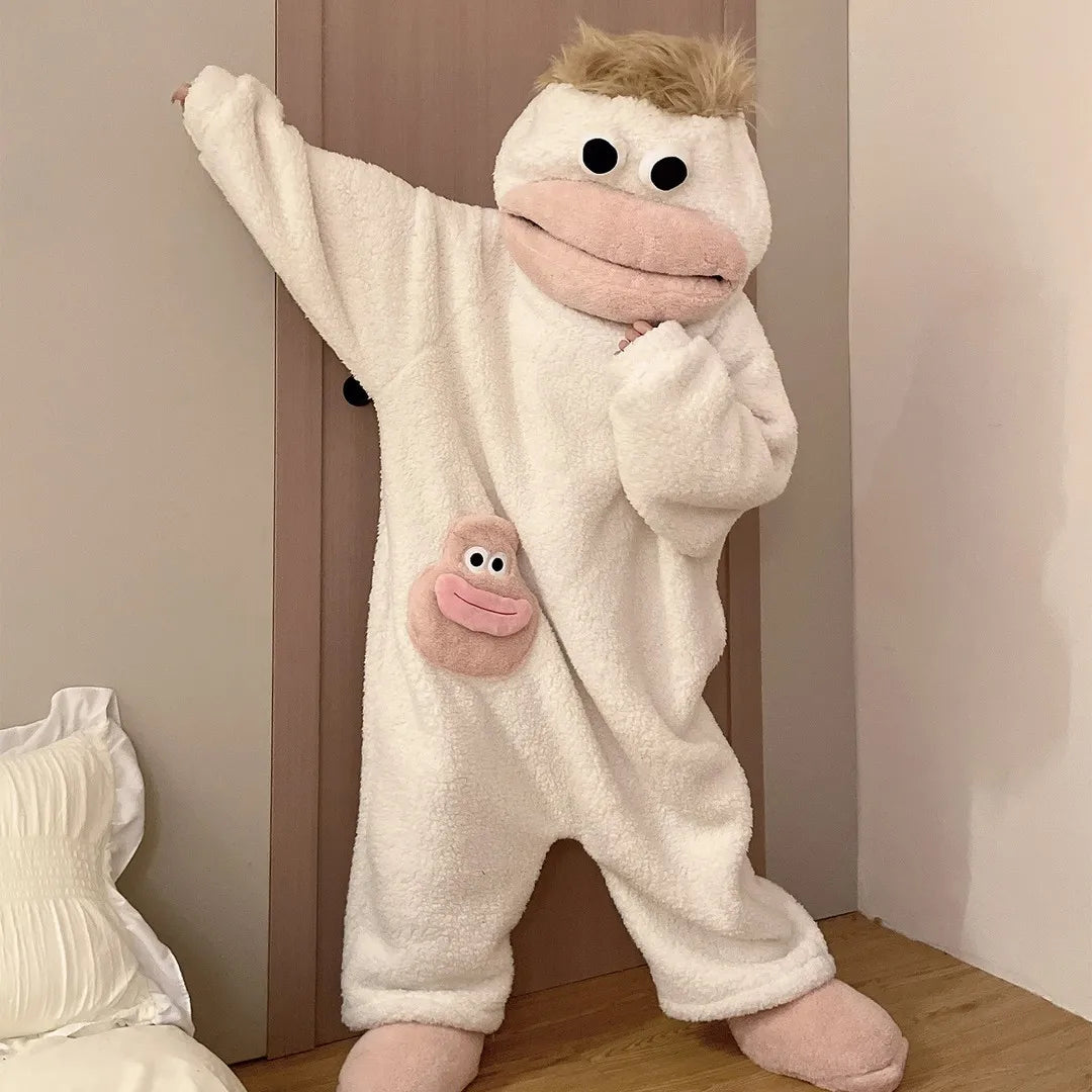 A white fuzzy monster onesie pajama set with pink accents is shown standing against a light wall.