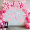 A pink balloon arch decorated with a happy birthday banner featuring pink bows and balloons.