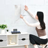 A woman is applying marble wall decals to a white tile surface in a modern setting.
