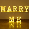 Luminous LED alphabet night lights spelling out MARRY ME on a wooden surface