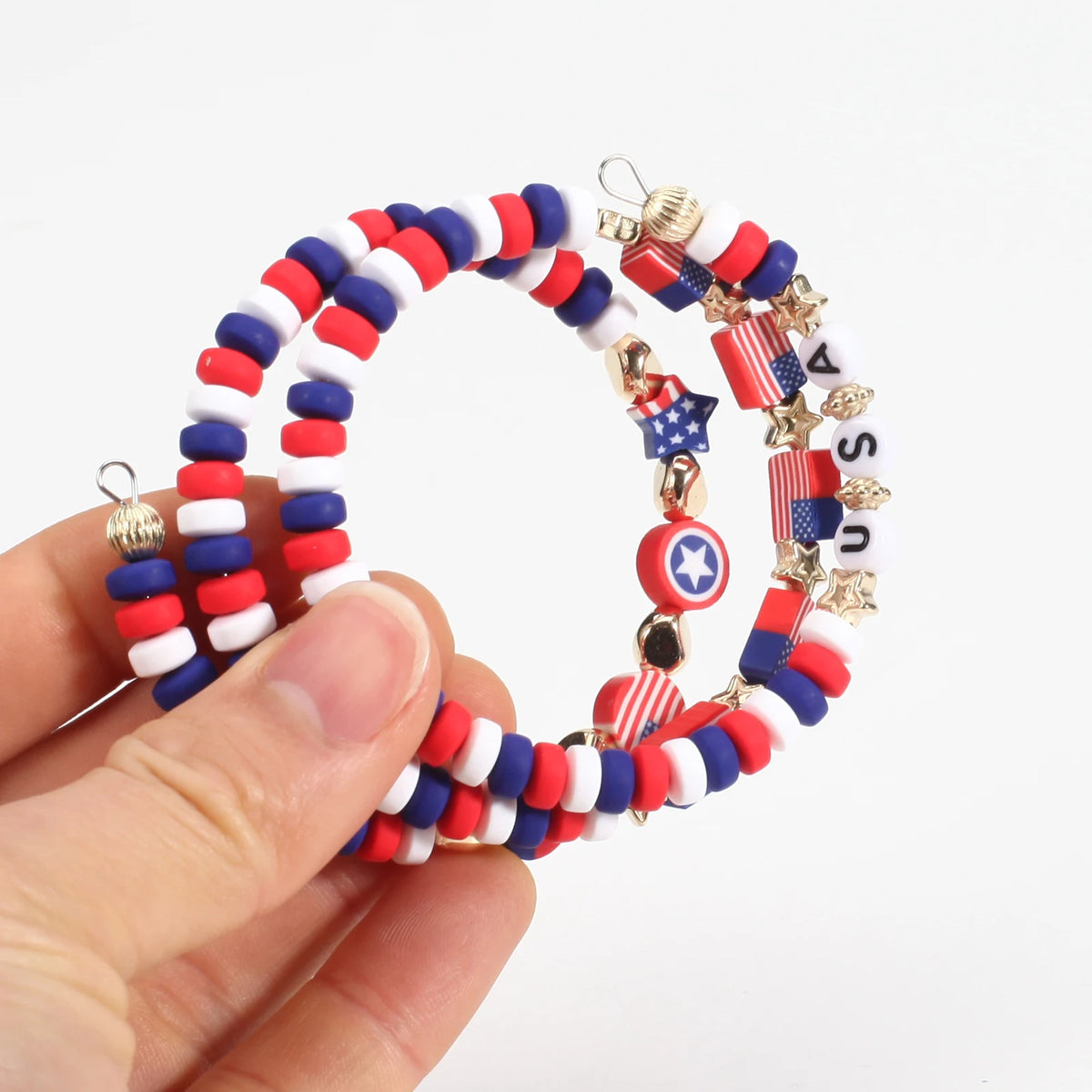 A hand holds a circular bracelet made of patriotic American flag beads in red, white, and blue.