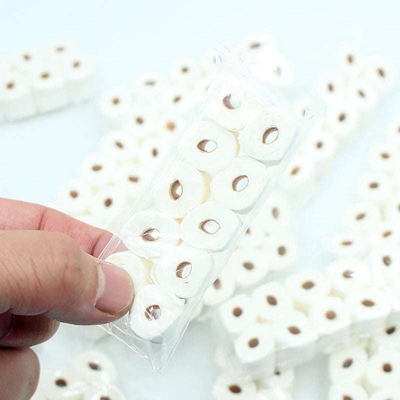 Une main tient un paquet de rouleaux de papier toilette miniatures pour décoration de maison de poupée