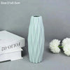 A tall, light mint green decorative plastic vase with vertical ribbed texture.