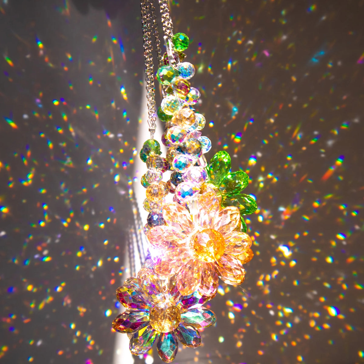 Gros plan d'un diffuseur de soleil en cristal de tournesol suspendu, avec des pétales de verre multicolores et des éclats de 