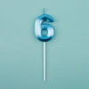A blue number six candle on a white stick against a light teal background.