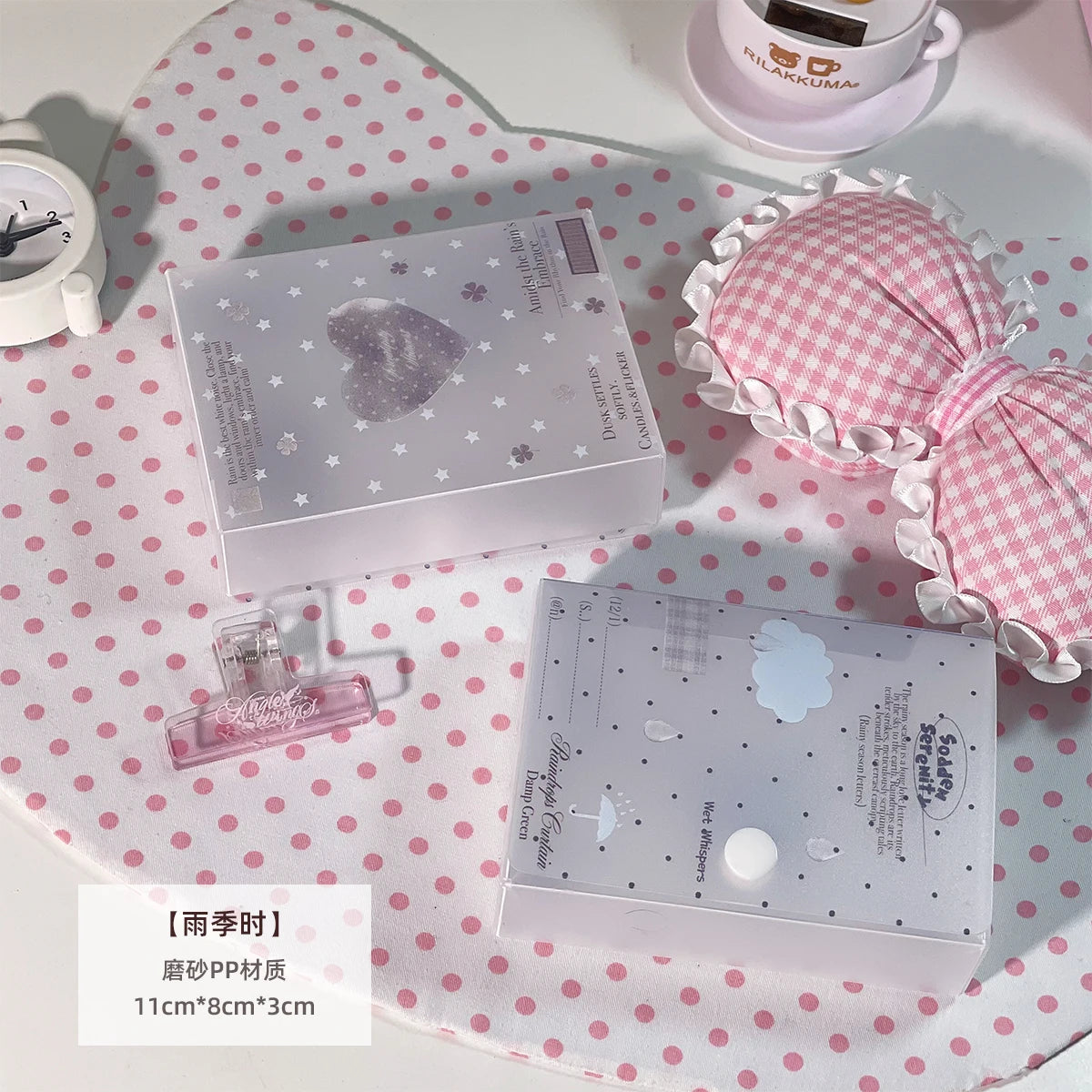 Una caja de almacenamiento minimalista blanca para pegatinas y cartas sobre un paño de lunares rosas con una taza y un vaso p