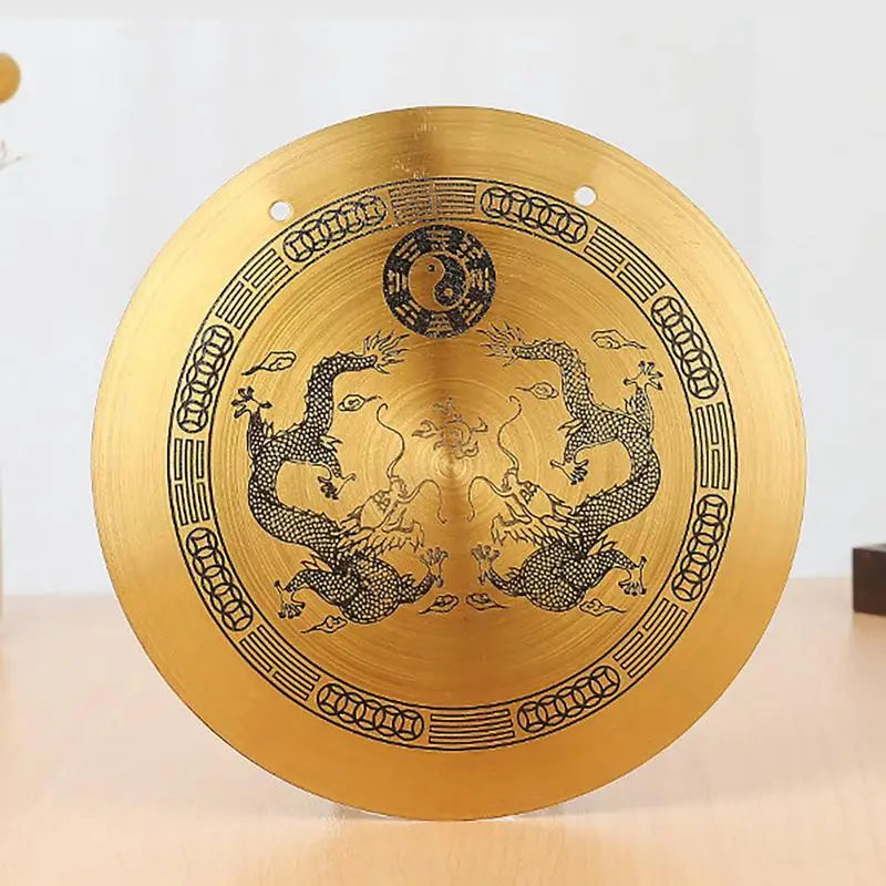 A round, brass Feng Shui Zen table gong featuring intricate designs of dragons and Taiji symbols.