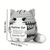 A handmade grey and white crochet mini cat plush with black stripes, featuring a sentiment about believing in the recipient.