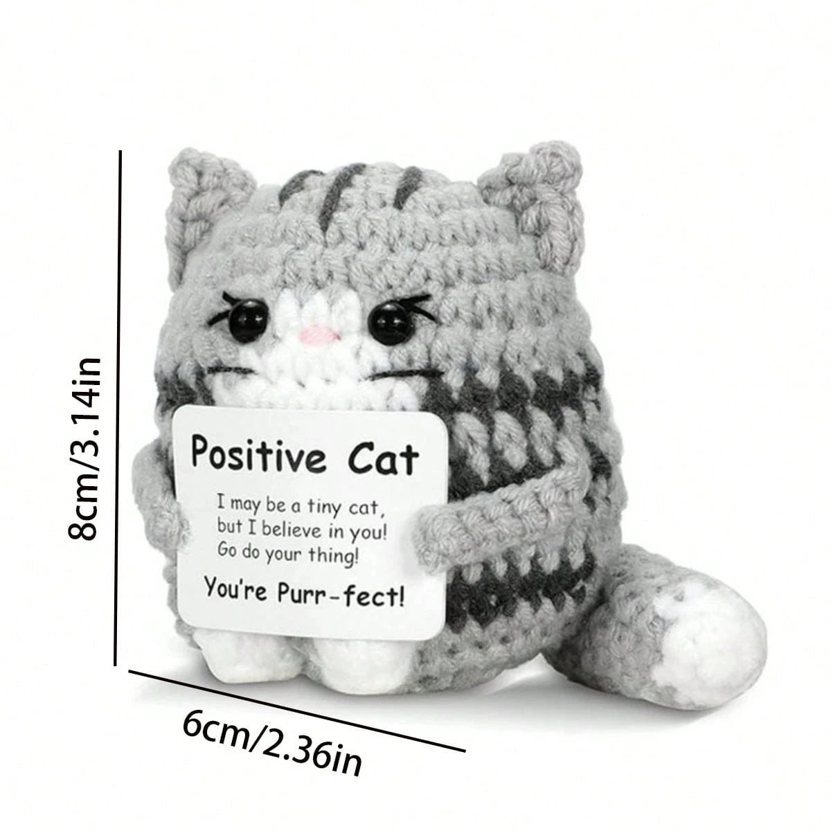 A handmade grey and white crochet mini cat plush with black stripes, featuring a sentiment about believing in the recipient.