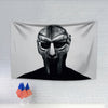 A black and white portrait of a stylized face on a gray fabric tapestry.