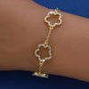 A gold-plated cubic zirconia flower bracelet is worn on a person's wrist.