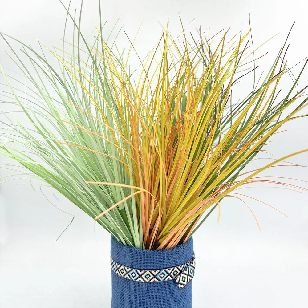A bundle of artificial grass greenery with variegated green and yellow blades in a blue pot.