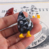 A hand holds a set of three playful chicken butt fridge magnets featuring black and white speckled chickens with yellow feet.