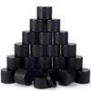 A stack of black candle tin containers with lids arranged in a pyramid shape.
