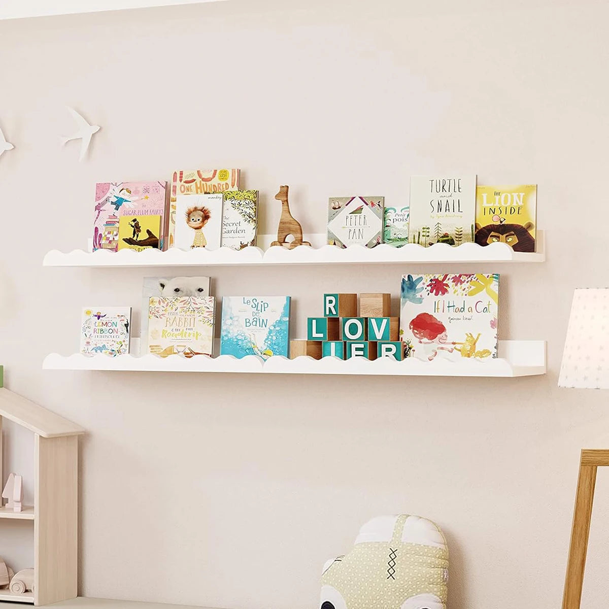 Two white wooden floating shelves display colorful children's books and decorative items.