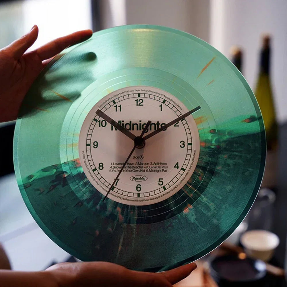 A hand holds a vintage vinyl record wall clock with a transparent green cover displaying the time.