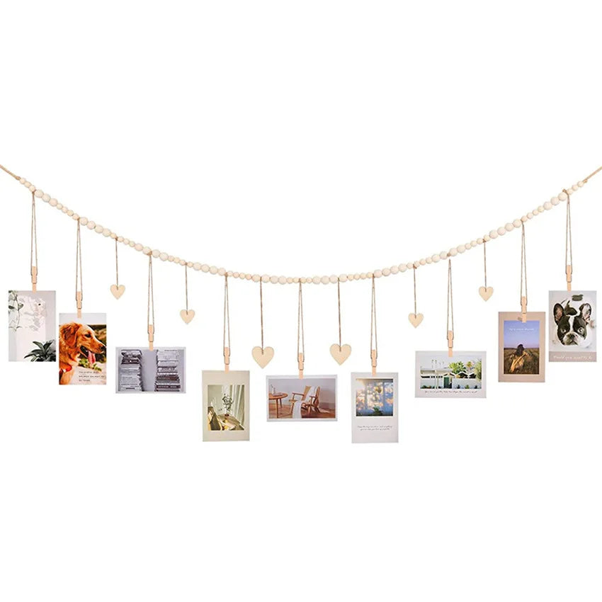 A delicate string of heart-shaped wooden hangers displaying various framed photos and artwork.