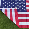 A double-sided American flag displayed on green grass.