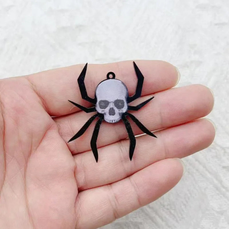 Un colgante de araña de acrílico negro con diseño de calavera sostenido en la mano de una persona.