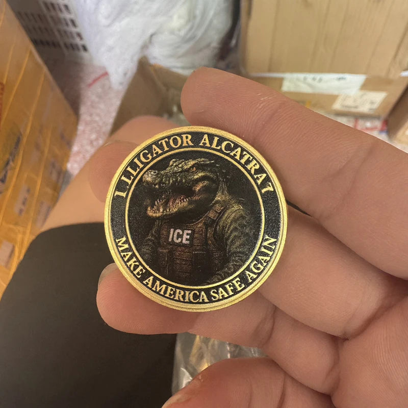 A hand holds a gold-colored collectible coin featuring an alligator and the text Make America Safe Again.