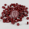 A pile of deep red wax sealing beads in various sizes and shapes for custom stamps.