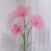 Large artificial silk pink poppy flowers displayed on a green stand against a white background.