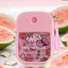 A pink bottle of Wish hydrating and moisturizing hand sanitizer spray with a lime and coconut fragrance next to cut guavas.