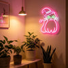 A neon light sign shaped like a black cat is mounted on a wall above potted plants.