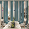 A modern living room featuring a teal wall with vertical acrylic mirror strips and light gray upholstered chairs.
