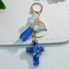 Gold-toned keychain featuring a blue resin butterfly charm and a blue cross pendant.