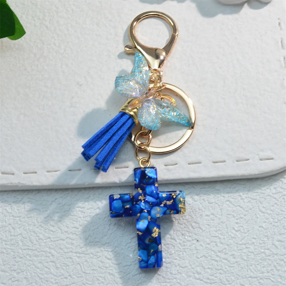 Gold-toned keychain featuring a blue resin butterfly charm and a blue cross pendant.