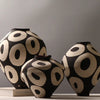 Two black and cream ceramic vases with geometric circle designs displayed on a white surface.
