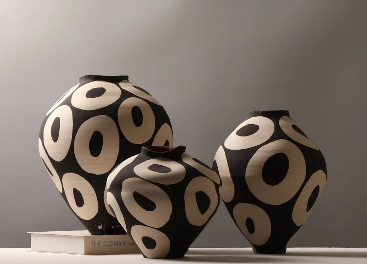 Two black and cream ceramic vases with geometric circle designs displayed on a white surface.