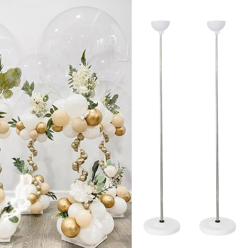 A set of adjustable metal balloon column stands with white and gold balloons displayed on a table.