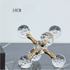 A minimalist molecular sculpture desk decor featuring gold-toned glass spheres with bubbles on a clear stand.