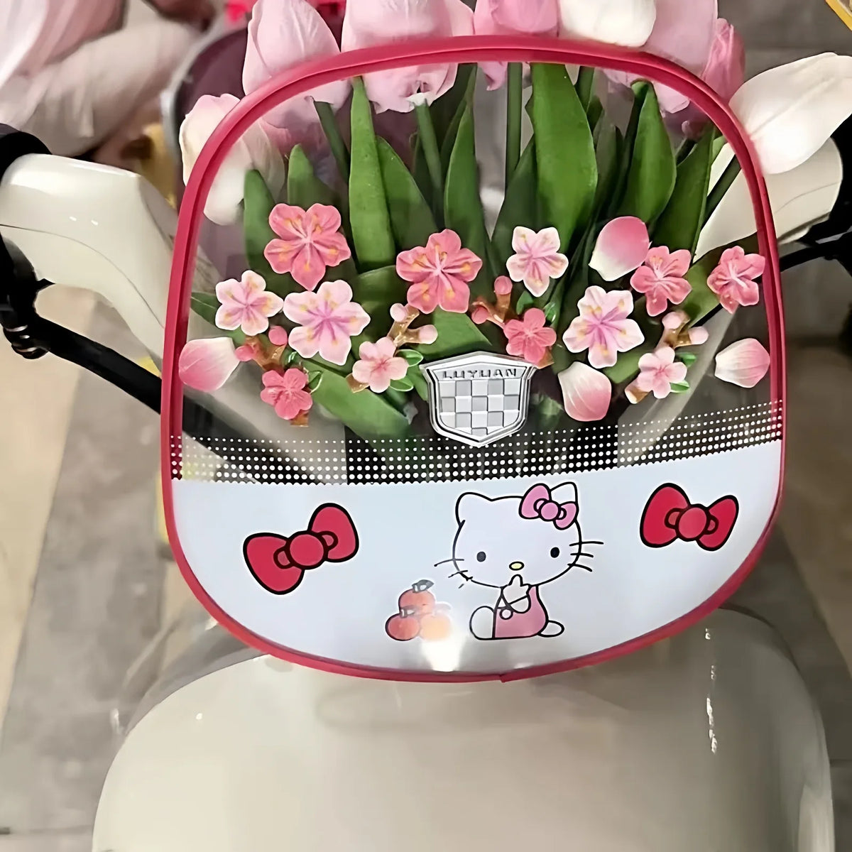 A dashboard ornament featuring pink flowers and a cat design on a white and pink background.