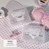 Una caja de almacenamiento transparente con tapa a cuadros rosa y blanco y un diseño de oso, colocada sobre un paño de lunare