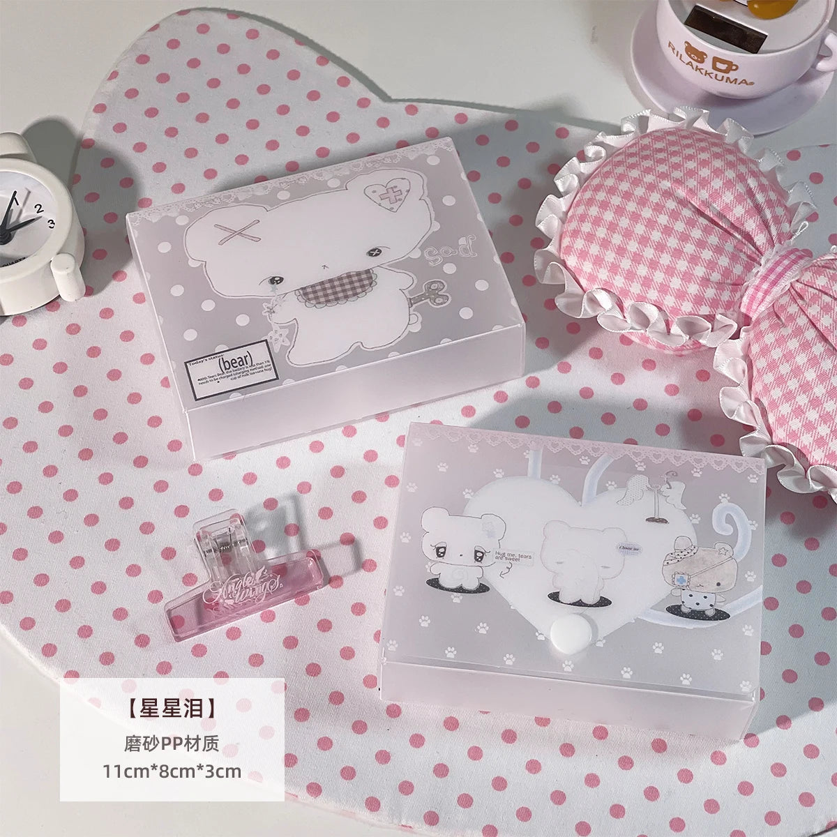 Una caja de almacenamiento transparente con tapa a cuadros rosa y blanco y un diseño de oso, colocada sobre un paño de lunare