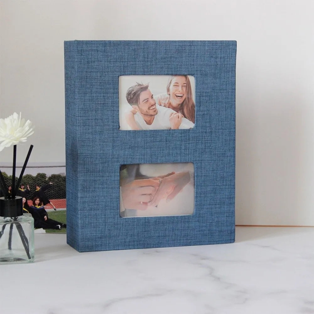 A blue linen-covered photo album with two square pockets displaying candid photos of a couple.