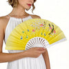A woman holds a yellow and white printed plastic folding fan with floral designs.